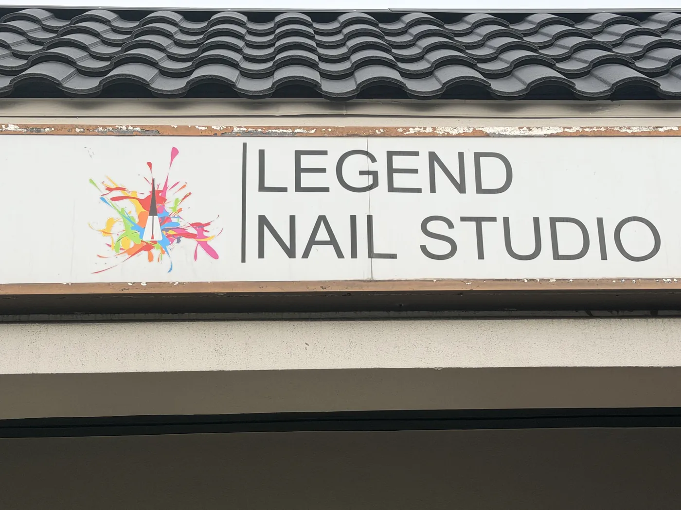 The Legend Nail Studio sign, showing the paint-splash logo beside the salon name